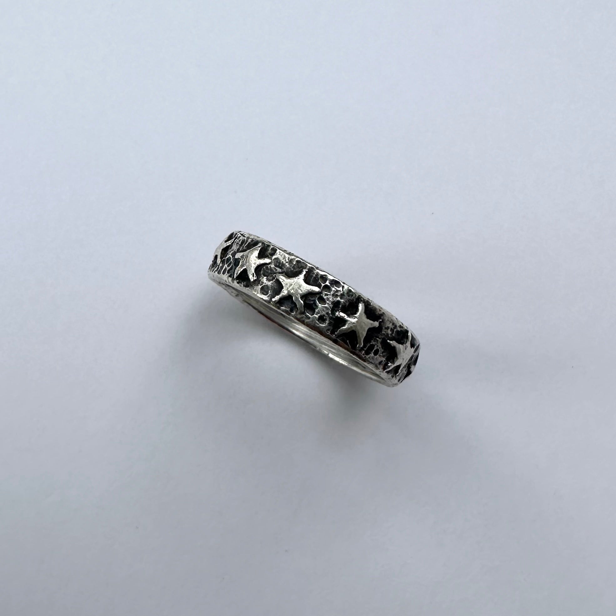 Silver ring with star designs on a light gray background
