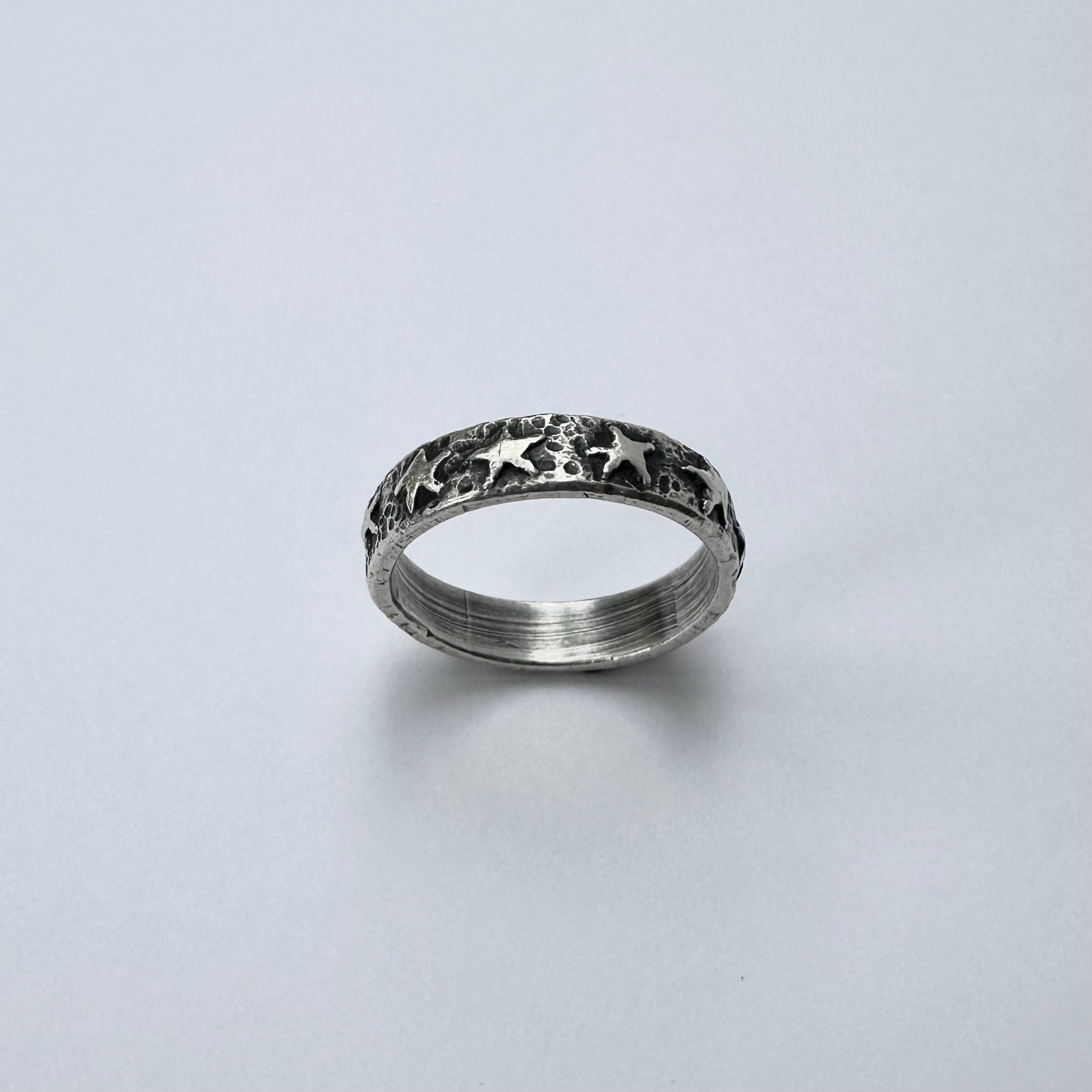 Silver ring with star patterns on a light gray background