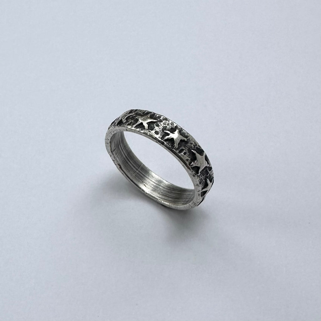Silver ring with star patterns on a light gray background