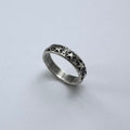 Silver ring with star patterns on a light gray background