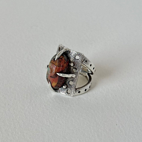 Boulder opal prong set on silver ring with textured background and split shank design.